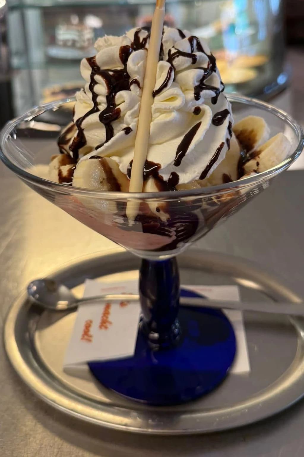 Eisbecher mit Sahne, Schokosauce, Bananenscheiben und Waffelröllchen