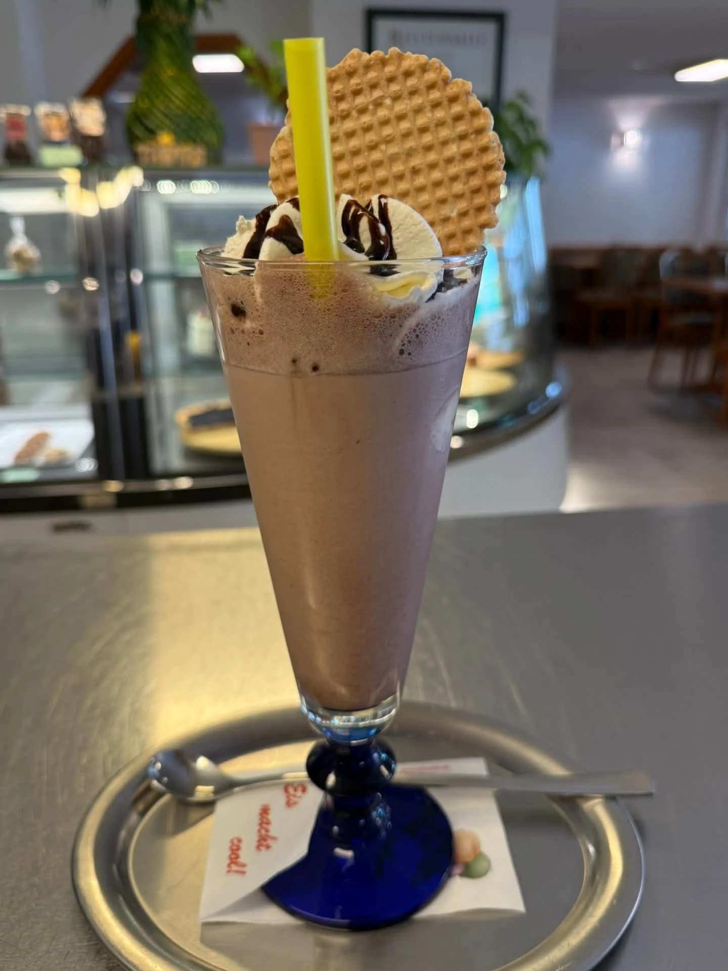 Hohes Glas mit Eiscreme, Strohhalm und Waffelkeks