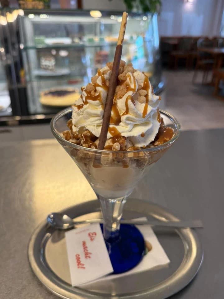 Eisbecher mit Sahne, Karamellsauce, Krokant und Waffelröllchen